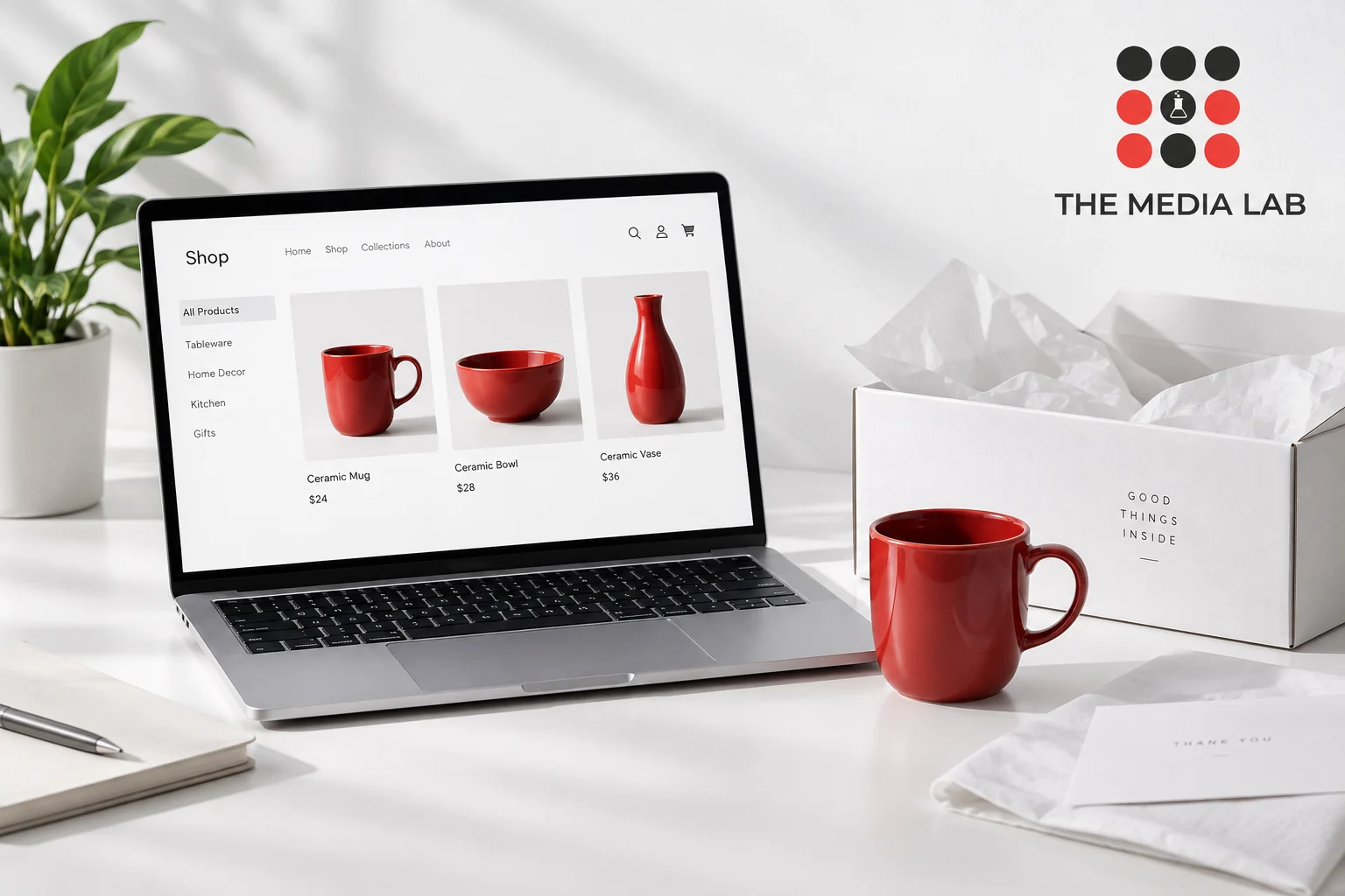 Laptop displaying an online ceramics store beside a red mug, illustrating The Media Lab’s ecommerce website guide.