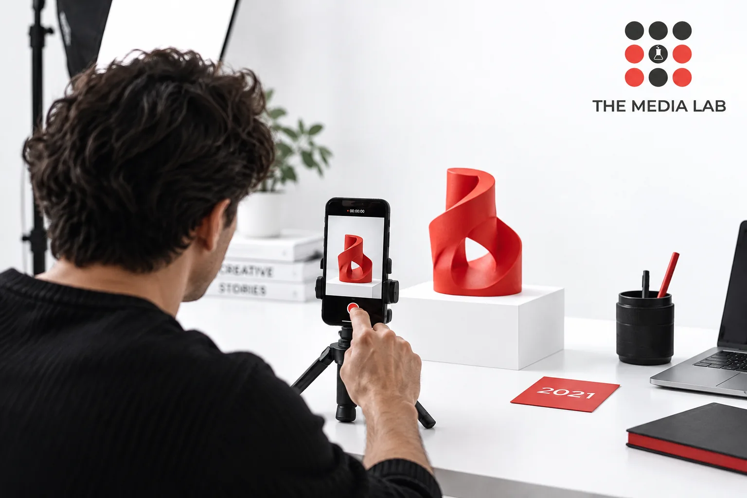 Creator filming a red sculpture beside a 2021 archive card — editorial illustration for The Media Lab.