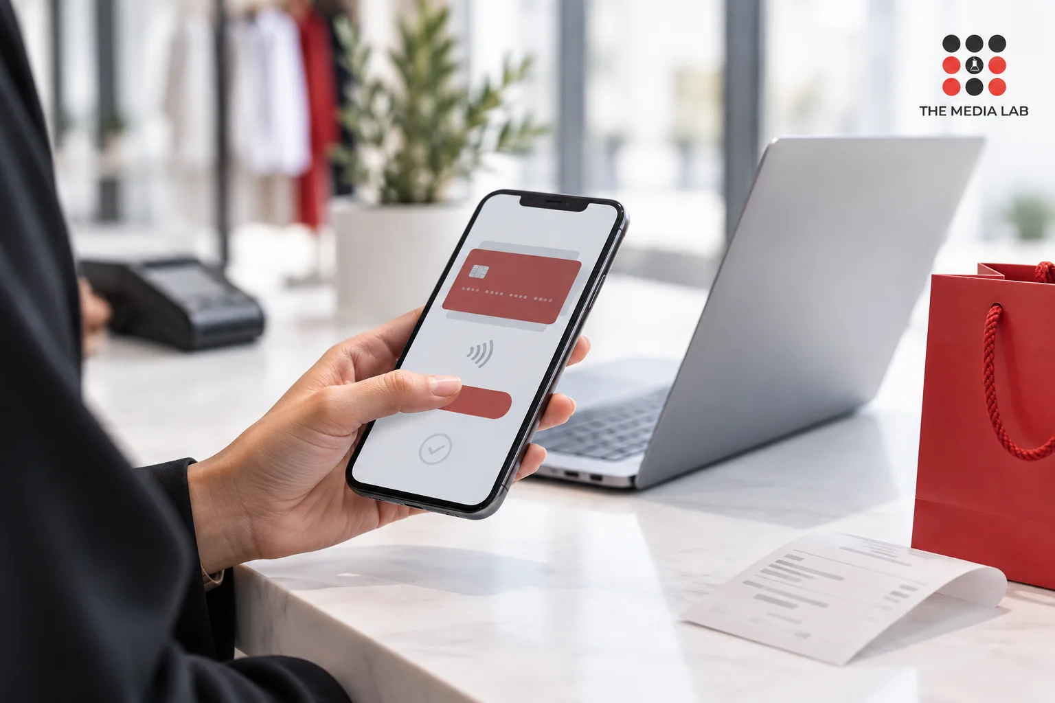 Phone showing an illustrative payment screen beside a laptop, created for The Media Lab’s UAE digital media guide.