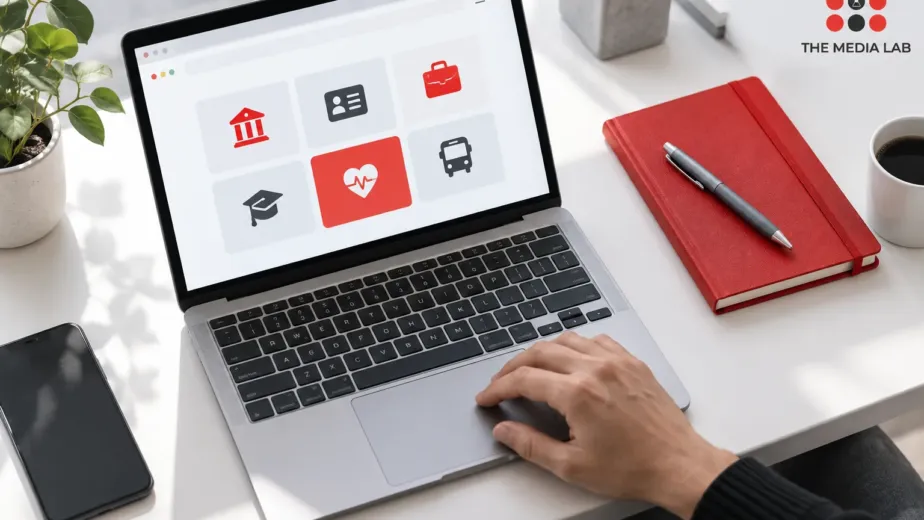 Laptop with service navigation tiles and a red notebook, illustrated for The Media Lab’s UAE website guide