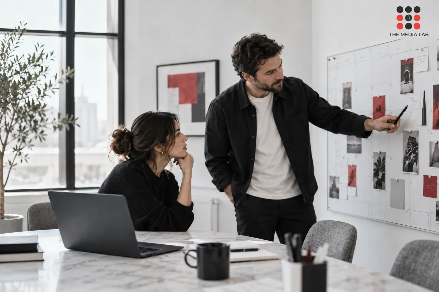 Business owner and social media producer reviewing a calendar in a bright minimalist meeting room — The Media Lab