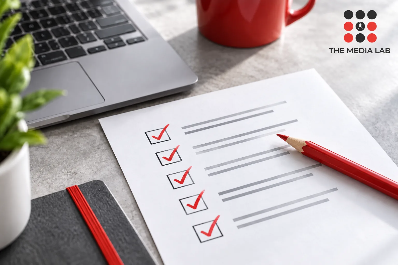 Website quality checklist with clear checked boxes, red pencil grey laptop — The Media Lab