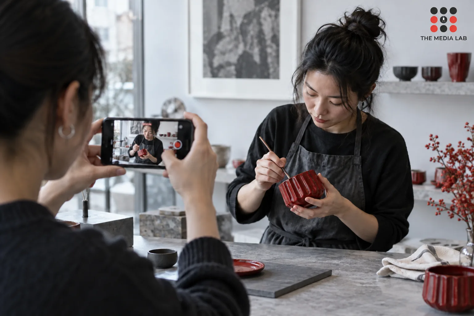 Phone filming a red handcrafted product demonstration at a shop counter — The Media Lab