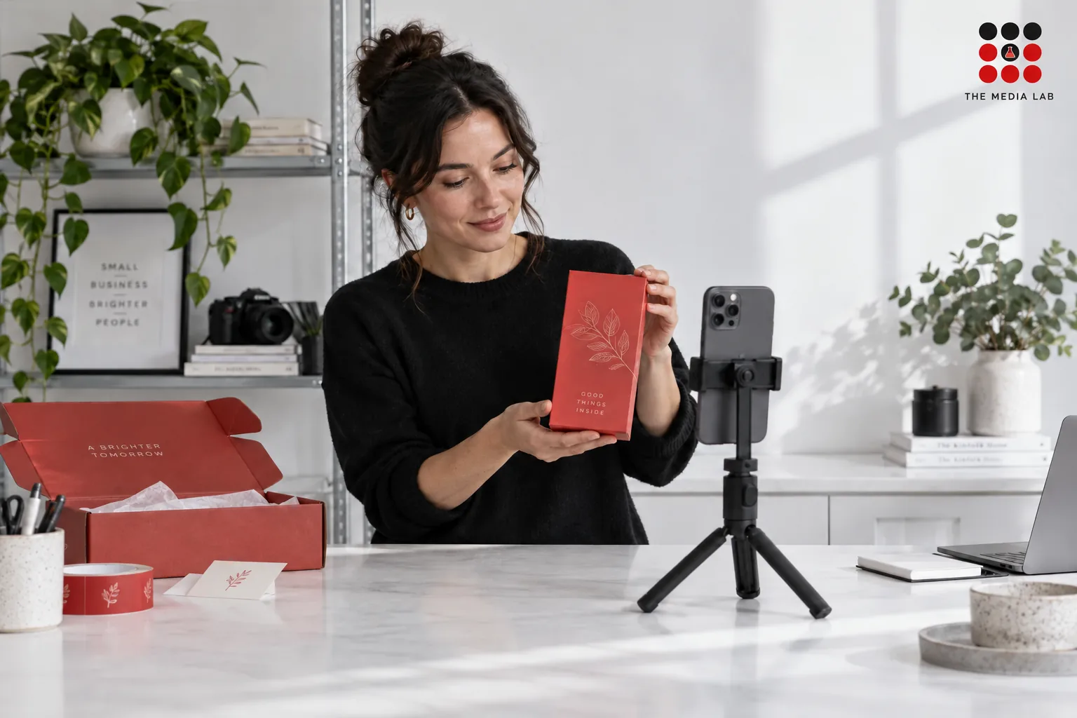 Small business owner filming a red product on a white counter — TikTok business illustration for The Media Lab.